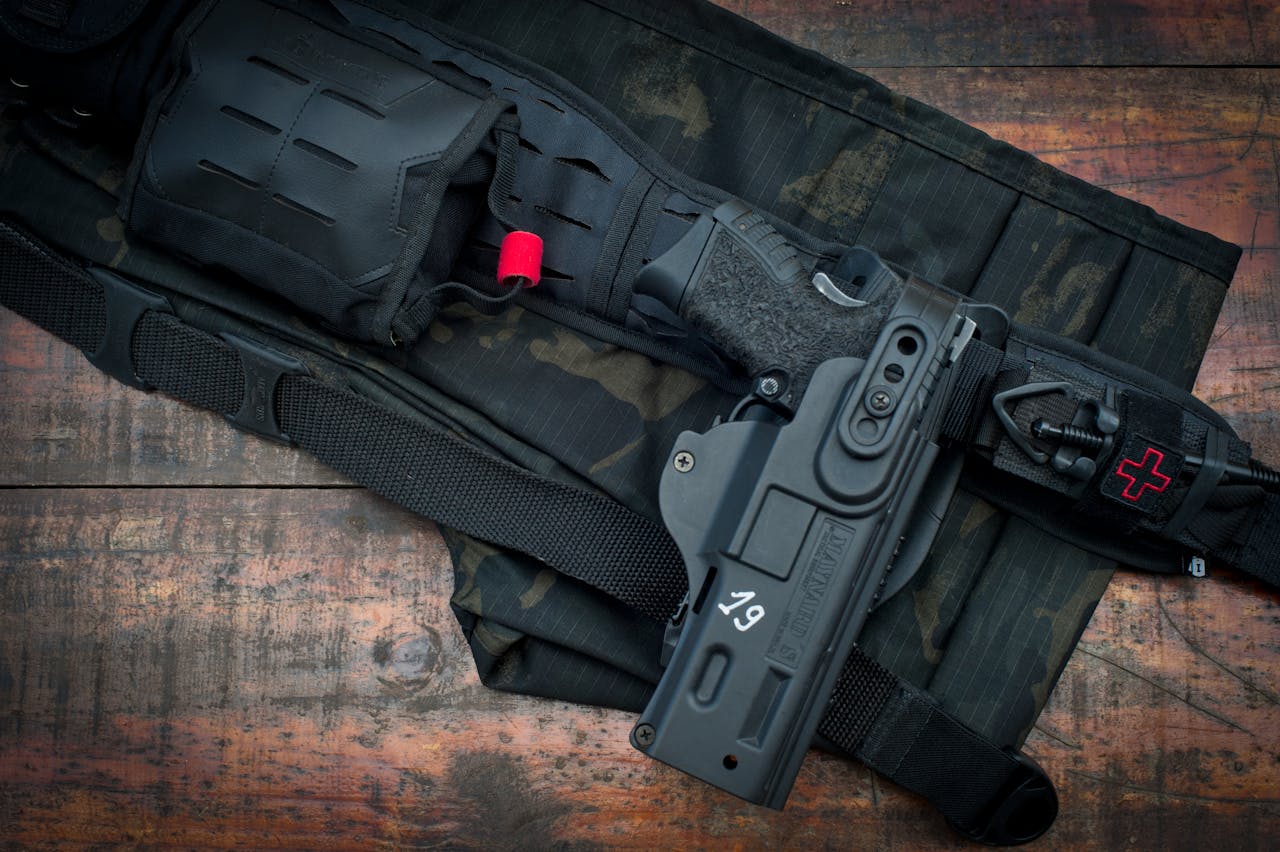 Close-up of tactical belt and handgun with camouflage pattern on wooden floor.