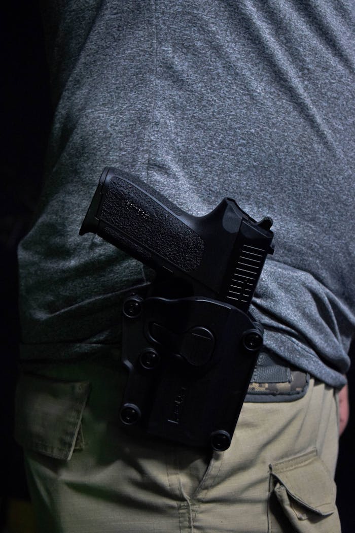 Close-up of a pistol securely placed in a holster on a person's hip.